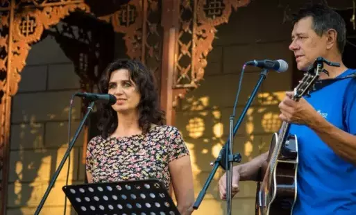 kobieta i mężczyzna śpiewająca scenie. Mężczyzna gra na gitarze.